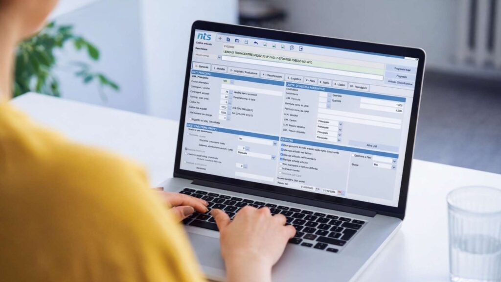 Una persona sta lavorando al laptop in un ufficio moderno, mentre visualizza una dashboard gestionale sullo schermo. L'ambiente è luminoso e organizzato, con elementi che riflettono l'uso di software gestionale in cloud per la gestione dei progetti e delle attività aziendali in tempo reale.